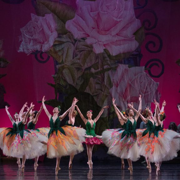 Dancers on stage with arms raised in air