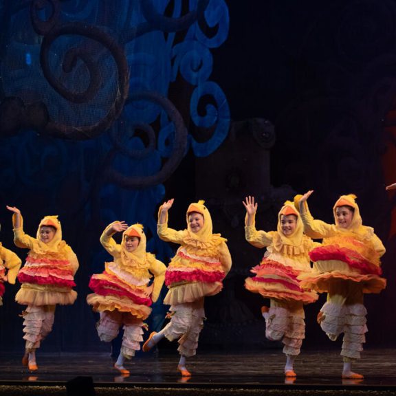 Dancers in duck costumes on stage waving