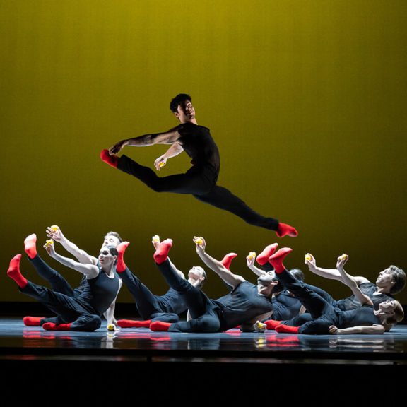Male Ballet Dancer Jumping On Stage in Front of Other Dancers