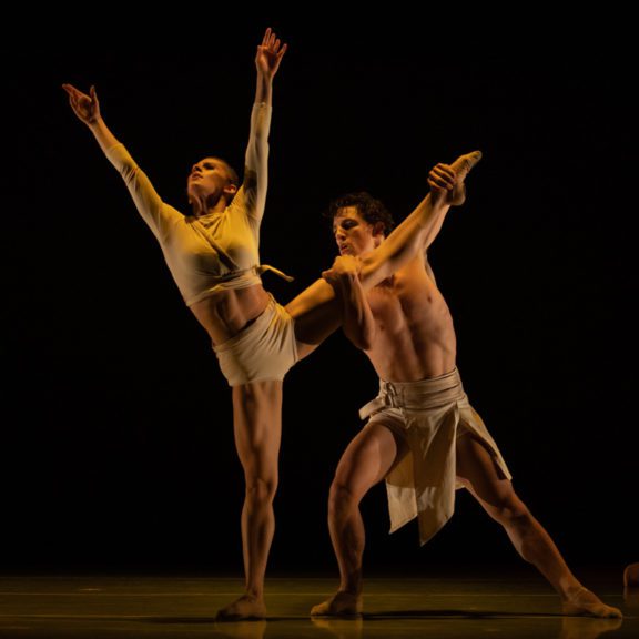 Two ballet dancers wearing white clothes on stage