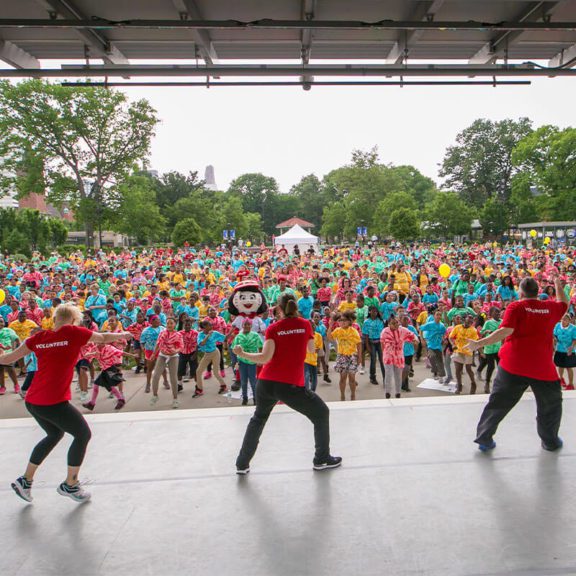 Volunteers dancing on stage in front of a large crowd