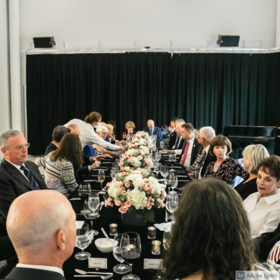 Photo of a group of people sitting at a long table during an event in a rented space at the Cincinnati Ballet campus