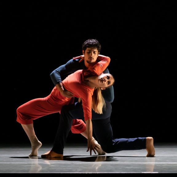 Photo of a male ballet dance down on his knees while holding up a female ballet dancer