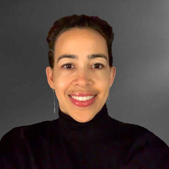 Photo of Chandra Moss Thorne wearing a black turtleneck sweater and smiling in front of a grey background
