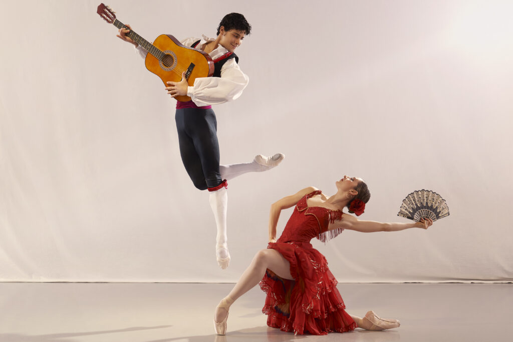 2023-2024 season | Photo of a male ballet dancer posing in the air with a guitar as a female ballet dancer poses on the floor with a hand fan during the Don Quixote show