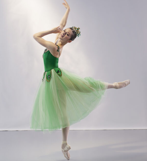 2023-2024 season | Photo of a female ballerina posing in a green dress and a gold/green crown