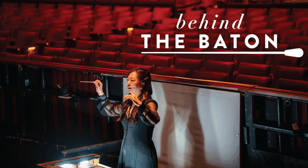 Alyssa Wang is standing in an orchestra pit while conducting